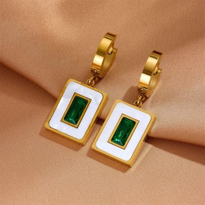 Detailed close-up of golden rectangular earrings with green gemstone and white enamel