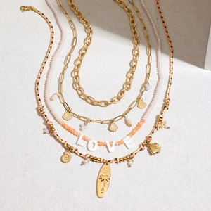 Layered gold necklace set with LOVE beads shell and palm tree surfboard pendants