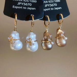 Détail macro de boucles d'oreilles perles baroques plaquées or 18k avec nœud et argent 925