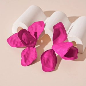 Macro detail of matte hot pink petal earrings on a white geometric display stand