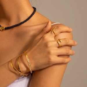 Macro detail of golden serpent rings and stacked bracelets with sparkling gemstones