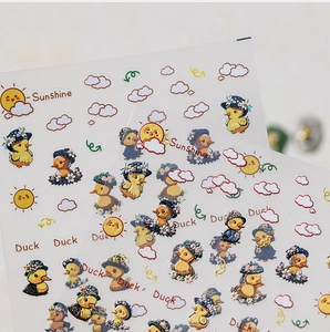 Close-up of yellow duck nail art stickers featuring sunshine and cartoon clouds