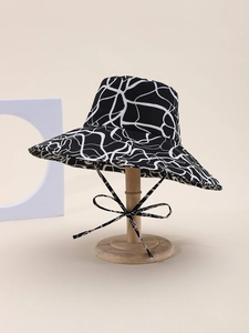 Detail of wide brim bucket hat with black and white abstract pattern and chin strap