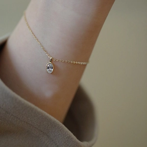 Detailed view of an oval clear crystal pendant on a gold chain necklace for women