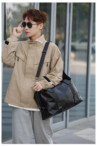 Model wearing large black PU leather travel bag in street style setting with modern background