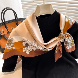 Detail view of floral print silk scarf styled on a neck form mannequin with a handbag