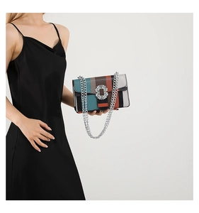 Detail of colorful striped crossbody bag with rhinestone buckle and silver chain strap