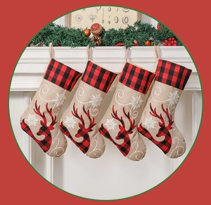 Detail of four Christmas stockings with reindeer embroidery hanging on a festive fireplace