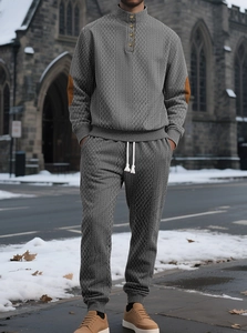 Detail of grey jacquard tracksuit with stand collar and brown elbow patch accents