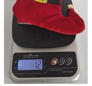 Detailed view of lightweight red felt Christmas stocking ornament weighing 12g on a scale