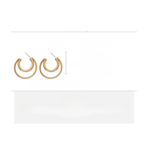 Detailed view of gold double hoop earrings with woven texture and silver needles