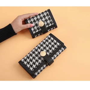 Detail of houndstooth wallet with gold circular snap button and multi-card slots