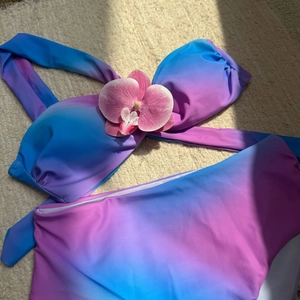 Vue à plat d'un bikini dégradé bleu-violet à taille haute sur une texture sablonneuse