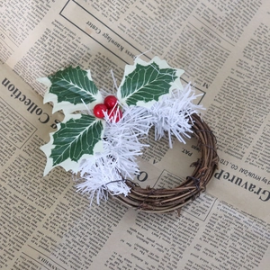 Détail de mini couronne de Noël avec baies rouges et épines de pin sur base de rotin