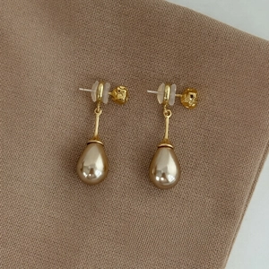 Elegant French vintage gold drop earrings with champagne pearls on brown fabric