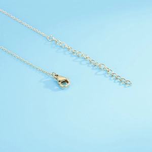 Macro shot of the gold necklace lobster clasp and extender chain on a blue background