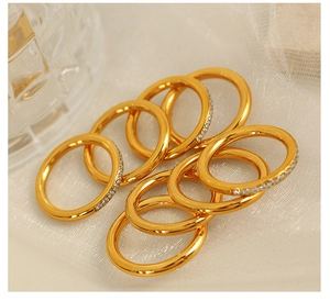 Set of nine golden rings featuring minimalist and crystal-studded designs on soft fabric