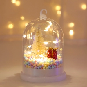 Close-up of glowing Christmas LED bell light with mini tree and festive ornaments inside
