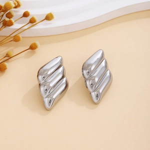 Macro detail of silver textured wavy triangle earrings on a modern minimalist pedestal