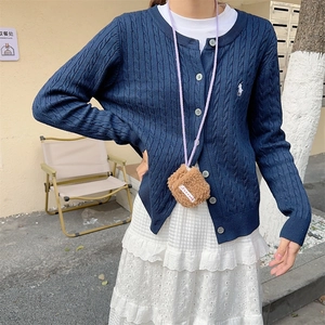 Mini brown fleece crossbody headphone bag paired with a navy cable knit cardigan sweater