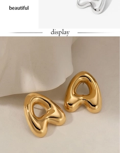 Macro shot of minimalist heart-shaped stainless steel earrings in polished gold and silver