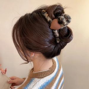 Détail d'une pince à cheveux en peluche léopard avec un accent de cœur sur les cheveux