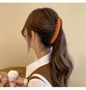 Matte caramel banana clip holding high ponytail in a lifestyle cafe setting