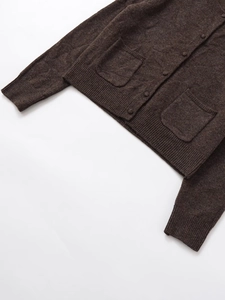 Detail of dark brown knit cardigan with front buttons, square pockets, and ribbed hem