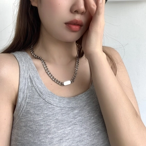 Detail of silver Cuban chain necklace with a smooth rectangular plaque on model