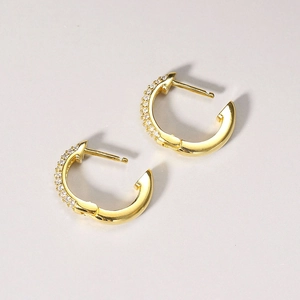 Detailed close-up of gold-plated C-shaped earrings with micro-pave white zircon stones