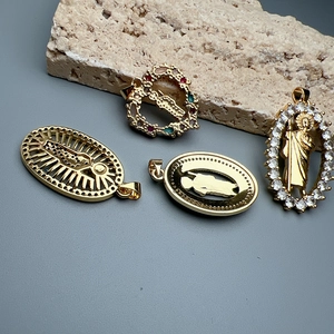 Detailed view of religious heart and oval pendants with colorful gemstones on a stone
