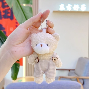 Llavero de oso de peluche crema con peto de textura gofrada y botones de madera decorados