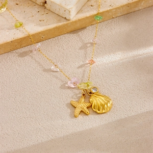 Gold starfish shell necklace with colorful stones on textured stone surface