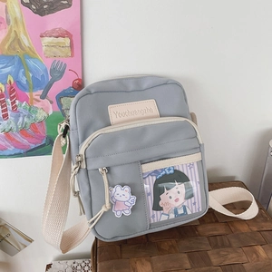 Détail du sac bandoulière en toile bleu clair avec poche transparente et breloque lapin