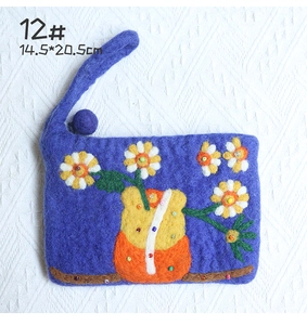 Detail of handmade wool felt pouch featuring colorful floral embroidery and bead accents
