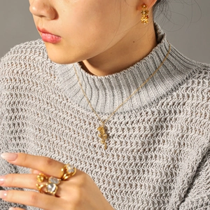 Detail view of gold rose flower necklace and matching earrings worn by a model