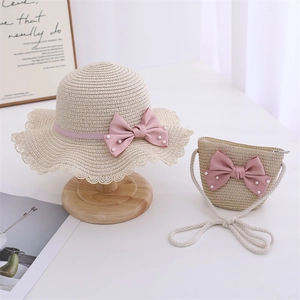 Detailed view of woven straw hat and matching bag with pink pearl bows for girls