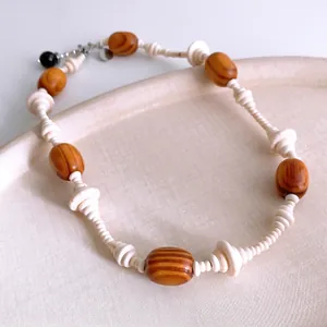 Ethnic style wooden bead necklace with oval stone pendant on a textured ceramic tray