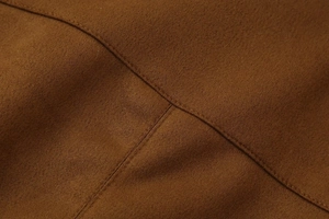 Close-up of caramel brown suede jacket featuring precise decorative stitching detail