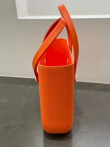 Detail of orange EVA handbag featuring side white rivet structure and faux leather texture
