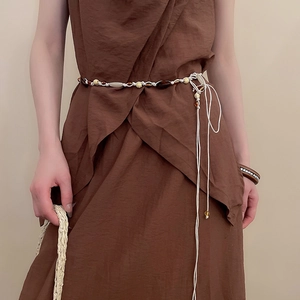 Detail of bohemian hand-woven waist chain with resin beads and long tassels on a dress