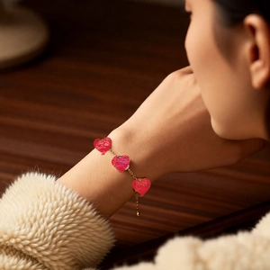 Gros plan du bracelet plaqué or 18 carats avec breloques cœur rouge sur le poignet