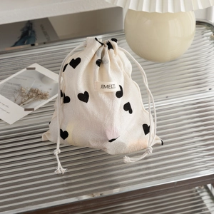 Close-up of champagne drawstring pouch with black heart patterns on glass surface