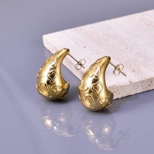 French vintage style gold drop earrings with embossed heart patterns on marble base