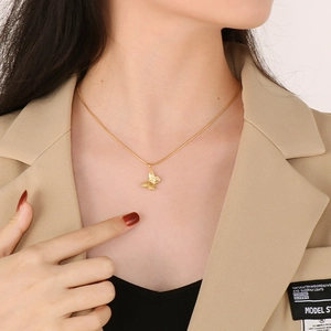 Elegant gold butterfly pendant necklace in titanium steel worn with a stylish blazer
