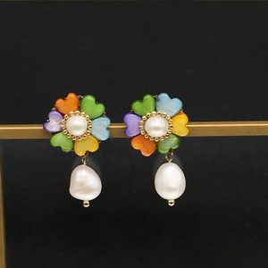 Macro detail of pearl drop earring with colorful flower petals on a black background