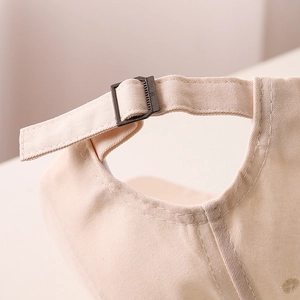 Detailed macro view of the adjustable metal buckle and beige cotton twill fabric on cap