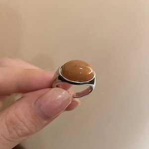 Macro view of adjustable silver ring featuring a large brown oval stone inlay