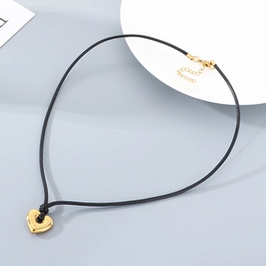 Close-up of golden heart pendant on adjustable black rope chain and extension link