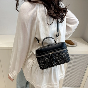 Retro crossbody box bag featuring black leather and gold tweed pattern on model